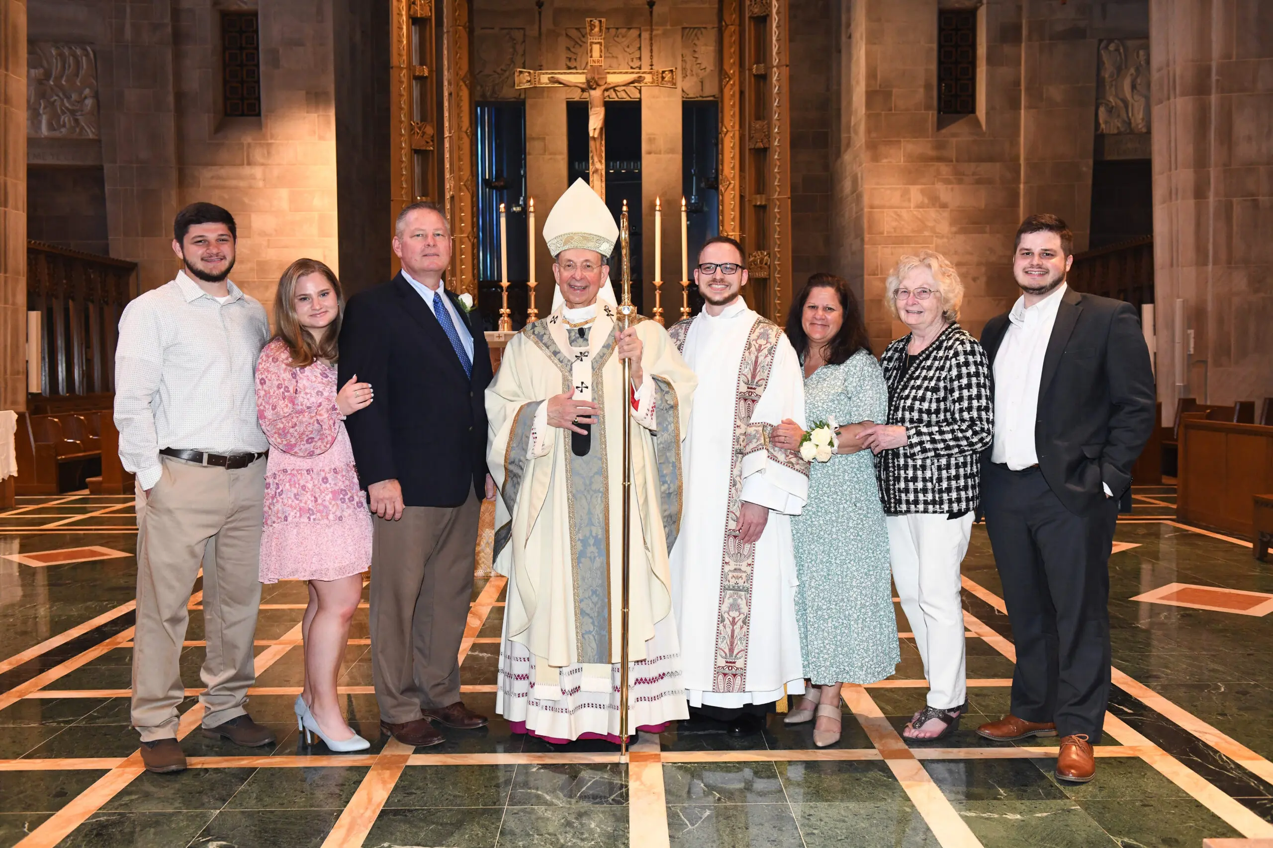 A family gathered around a priest and deacon.