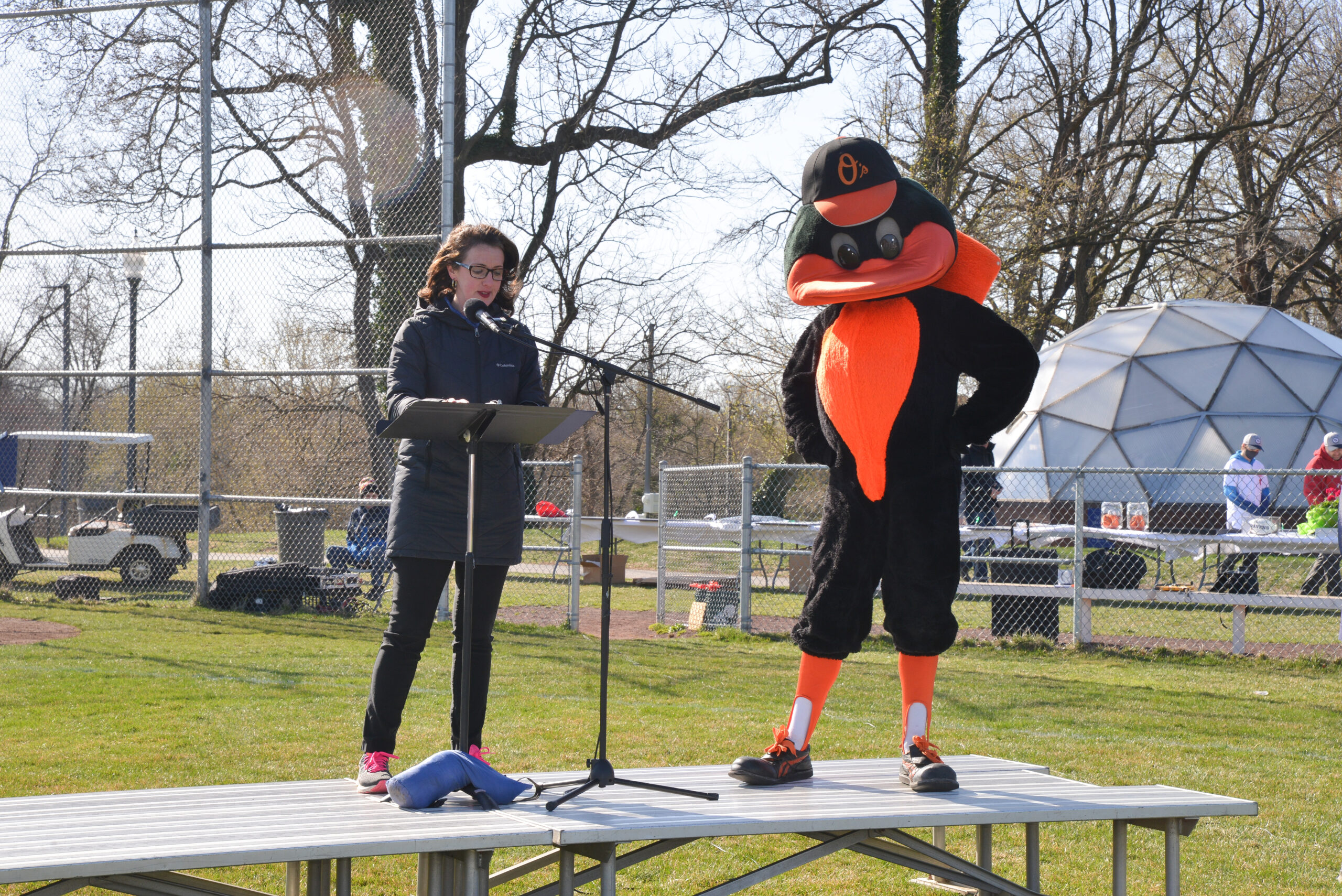 A woman and the Oriole's mascot on an outdoor stage