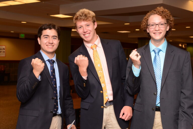 Three boys displaying their rings on their hands